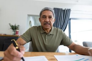 Hombre hispano de mediana edad revisando facturas en mesa de madera para entender el debt settlement