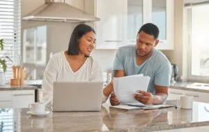 Pareja hispana revisando documentos en casa para reconstruir crédito después de un alivio de deudas