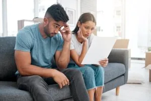 Pareja hispana revisando documentos de deuda con preocupación — cómo hablar con un cobrador de deudas en EE.UU.