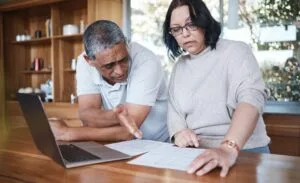 Pareja madura analizando documentos para entender la diferencia entre debt settlement y debt management en su hogar