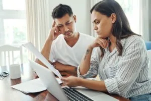 Pareja hispana de mediana edad estresada revisando documentos de deudas y papeles legales en casa