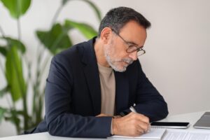 Hombre de mediana edad con gafas firmando documentos del capítulo 7 bancarrota estados unidos en oficina