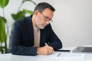 Hombre mayor de negocios firmando documentos sobre prescripción de deudas en estados unidos