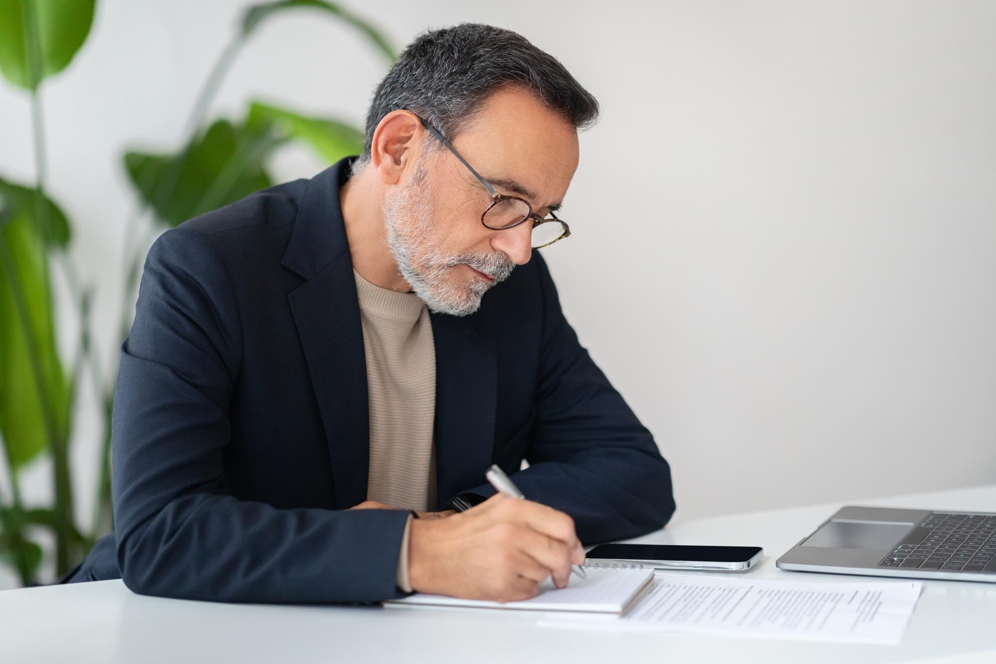 Hombre mayor de negocios firmando documentos sobre prescripción de deudas en estados unidos
