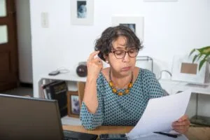 Mujer madura revisando cartas de deudas en colecciones con preocupación en su hogar